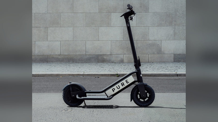 Pure Escape electric scooter parked against a stone wall